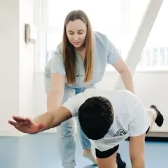 Fizjoterapeutka wspiera pacjenta w ćwiczeniach, które mogą obejmować mobilizację tkanek miękkich.