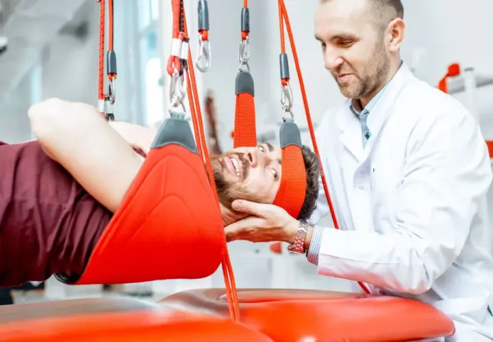 Fizjoterapeuta wspiera pacjenta podczas terapii wiszącej, która pomaga w leczeniu problemów z kręgosłupem.