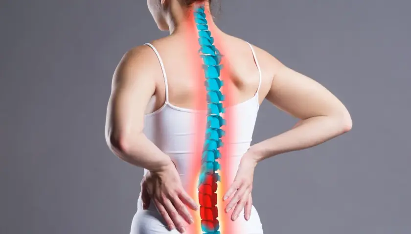 Kobieta odczuwa ból pleców, który może być jednym z objawów osteoporozy. Kręgosłup zaznaczony na czerwono.