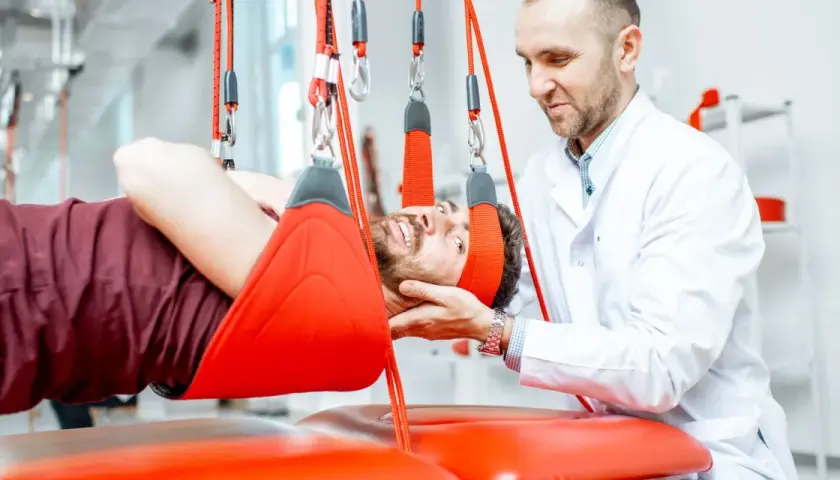 Fizjoterapeuta wspiera pacjenta podczas terapii wiszącej, która pomaga w leczeniu problemów z kręgosłupem.