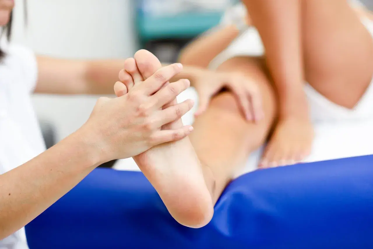 Fizjoterapeuta bada stopę pacjenta, oceniając potencjalną asymetrię chodu.