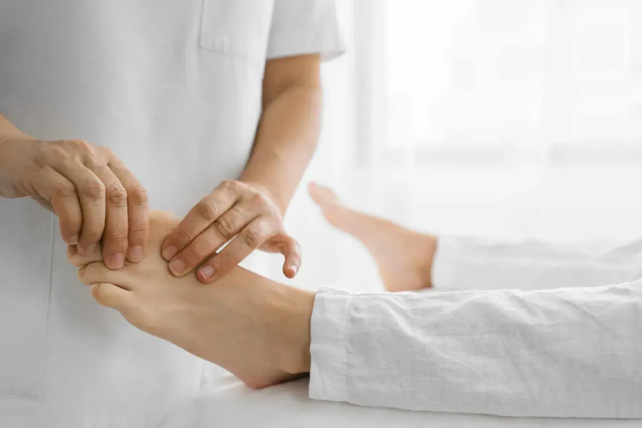 Fizjoterapeuta delikatnie masuje stopę pacjenta, pomagając w rehabilitacji opadającej stopy.