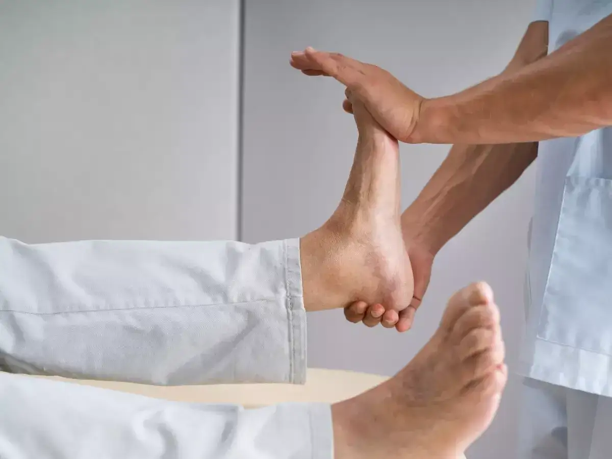 Fizjoterapeuta delikatnie masuje stopę pacjenta, pomagając w rehabilitacji opadającej stopy.