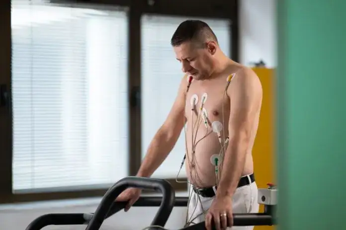 Pacjent ćwiczący na bieżni w ośrodku rehabilitacji kardiologicznej pod nadzorem personelu medycznego
